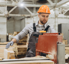 Tradesman Cutting Wood in Factory Setting